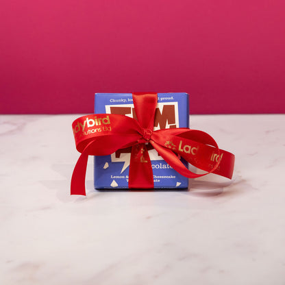 Temprd chocolate with a Personalised Stort Valley red ribbon on a white surface against a pink background
