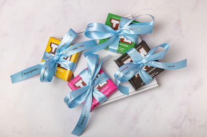 Assorted chocolate bars with blue ribbons on a light surface