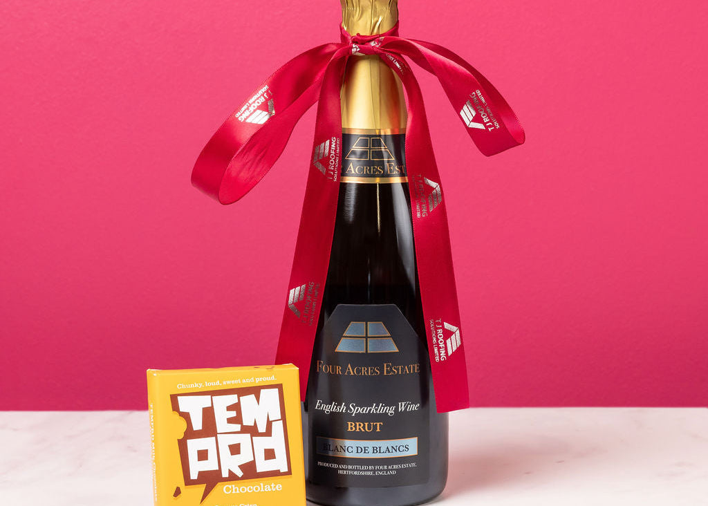 Bottle of English Sparkling Wine with a red ribbon against a pink background