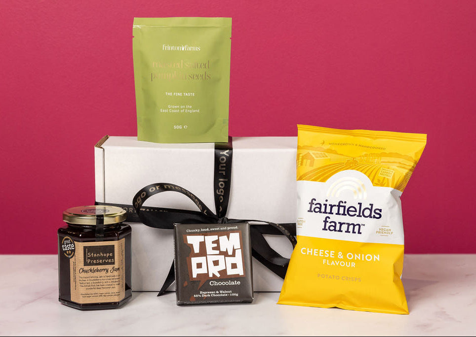 Stort Valley Gifting Hamper containing assorted food products including a green bag, yellow bag, and a jar on a pink background