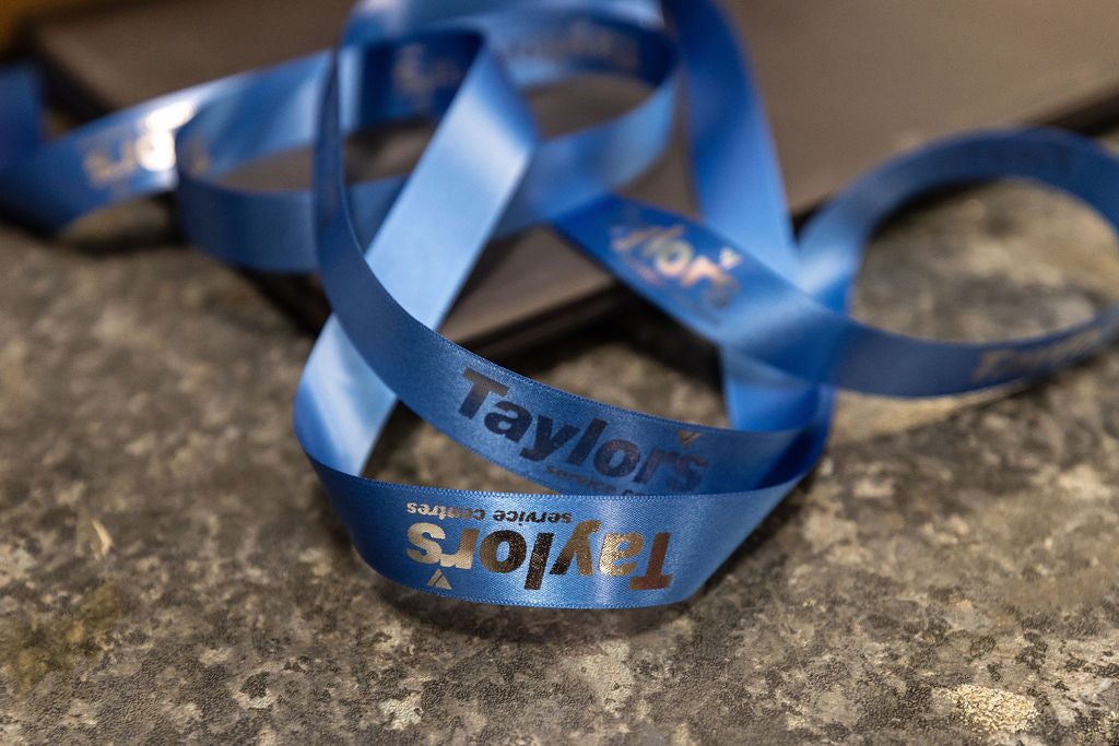 Blue ribbon with 'Taylor's' branding on a stone surface for personalised gifts from Stort Valley Gifting