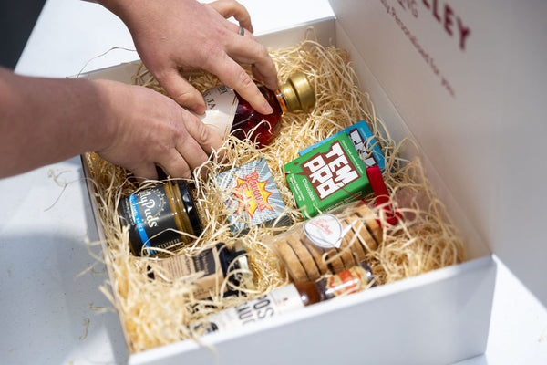 Personalised Stort Valley Gift Box filled with miniature bottles and packaging, being handled by a person.