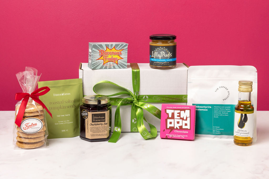 The Stort Valley Gifting celebration gift box including: Assorted products including a box, cookies, and jars on a pink background