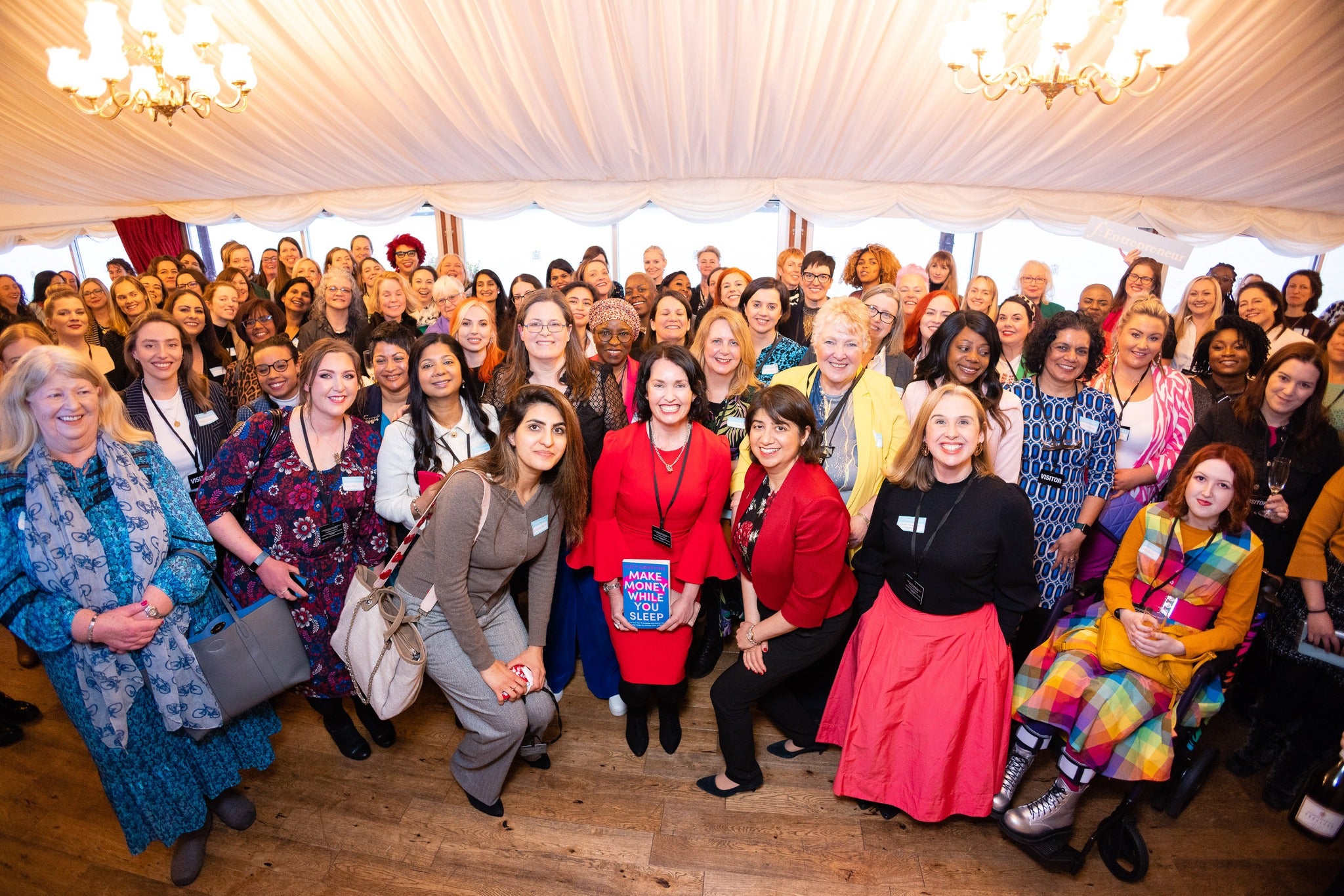 Group of FEntrepreneur women posing for a photo in a room with chandeliers.