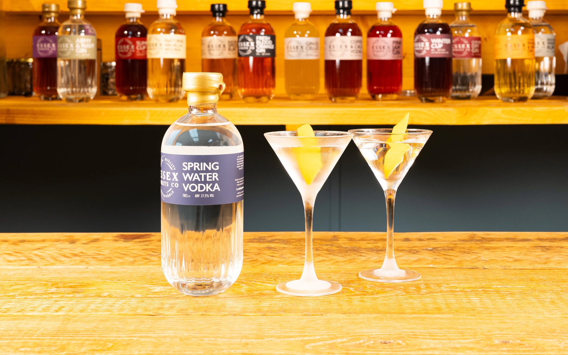 Bottle of 'Spring Water' vodka with two cocktails on a wooden bar counter available at Stort Valley Gifting