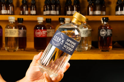 Hand holding a bottle of Essex Vodka with a blurred background of other bottles available at Stort Valley Gifting