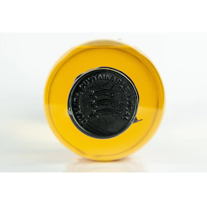 Yellow bottle cap with a black wax seal logo of the Essex Spirits Co. on a white background