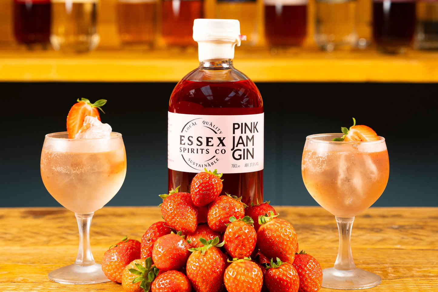 Essex Spirits Co Pink Jam Gin bottle with strawberries and cocktails on a wooden surface available at Stort Valley Gifting