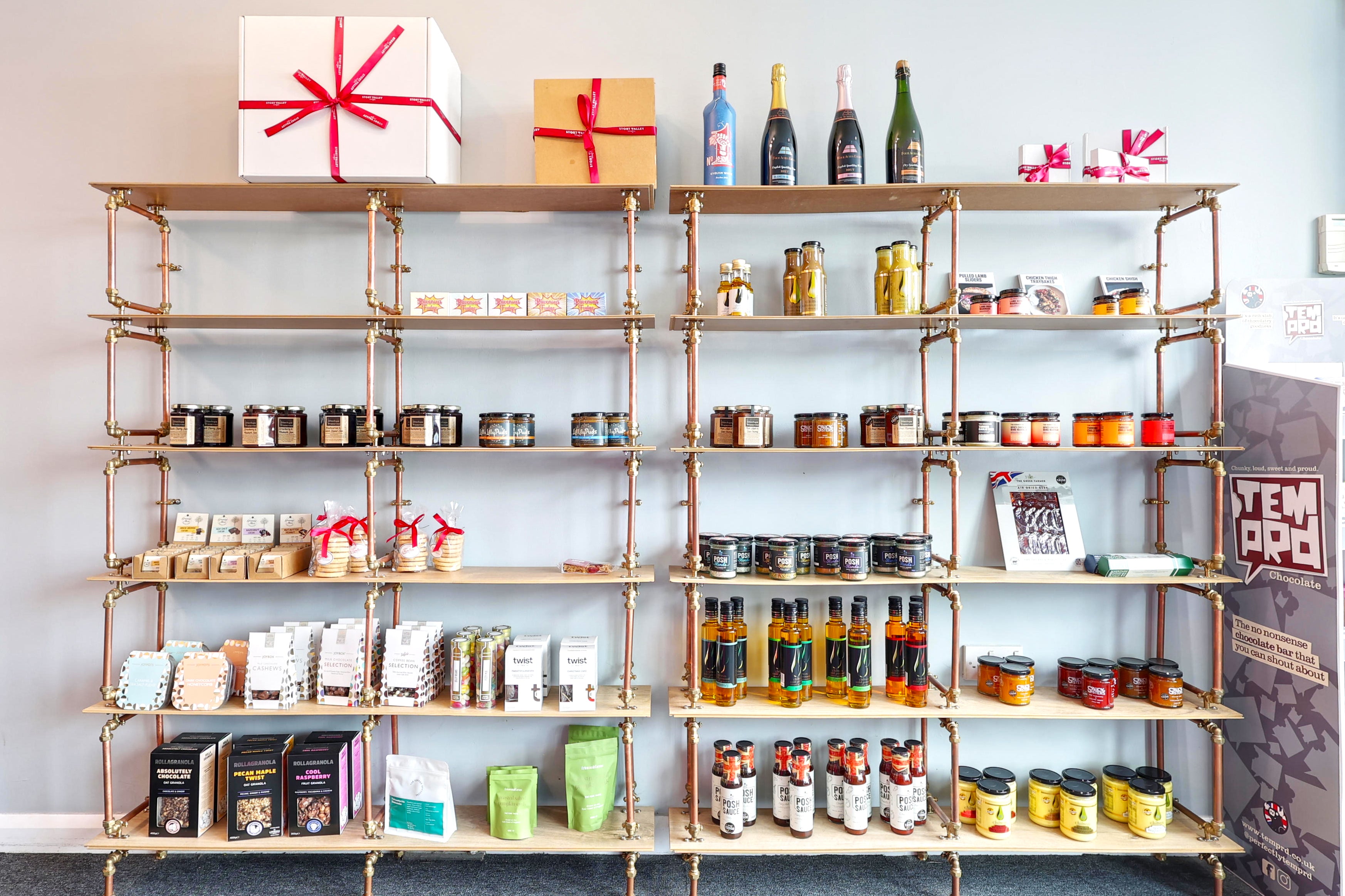Shelves at the Stort Valley Gifting Hamper hub with various products against a light blue wall