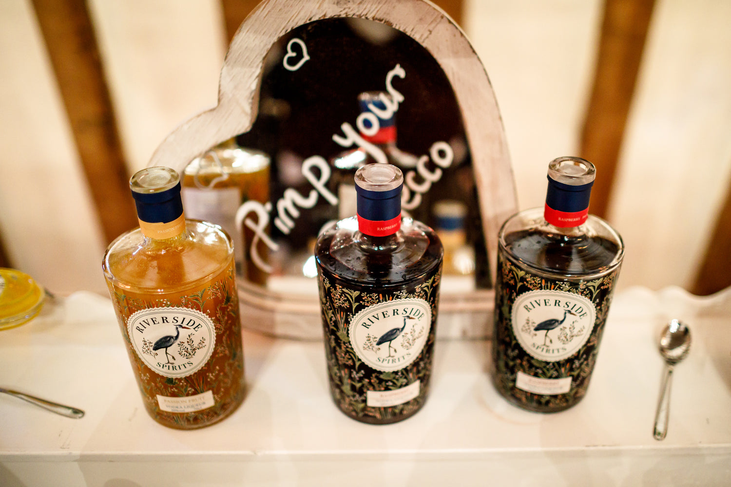 Three bottles of Riverside spirits gin on a bar counter with a decorative mirror in the background.