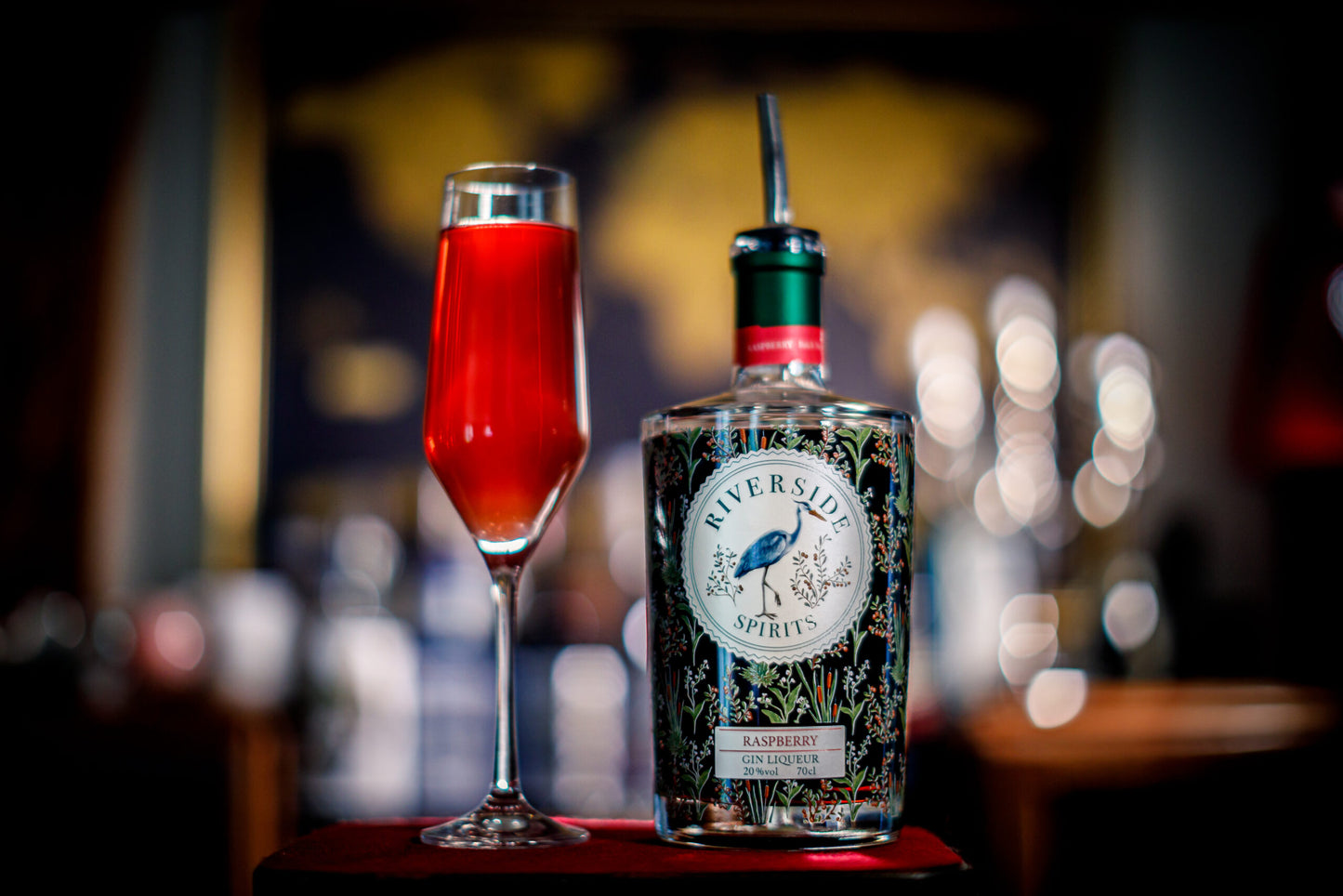 Riverside Spirits Raspberry Gin Liqueur bottle with a red cocktail in a champagne flute