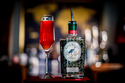 Riverside Spirits Raspberry Gin Liqueur bottle with a red cocktail in a champagne flute