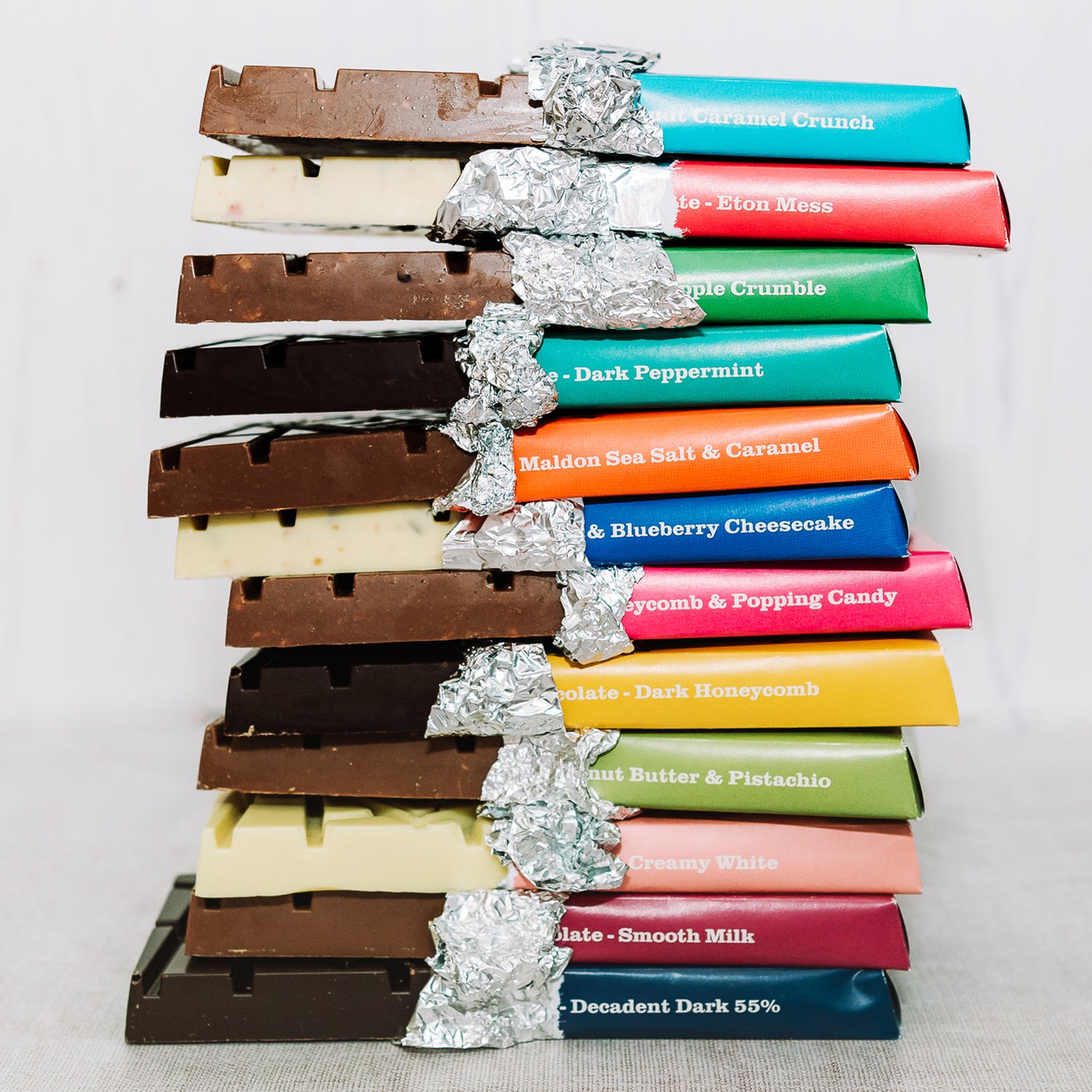 Stack of various Temprd chocolate bars with colourful wrappers on a light background