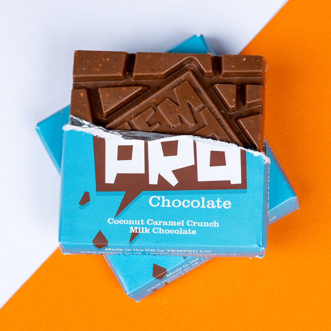 Temprd coconut caramel crunch milk Chocolate bar with a blue wrapper on an orange and white background available from Stort Valley Gifting 