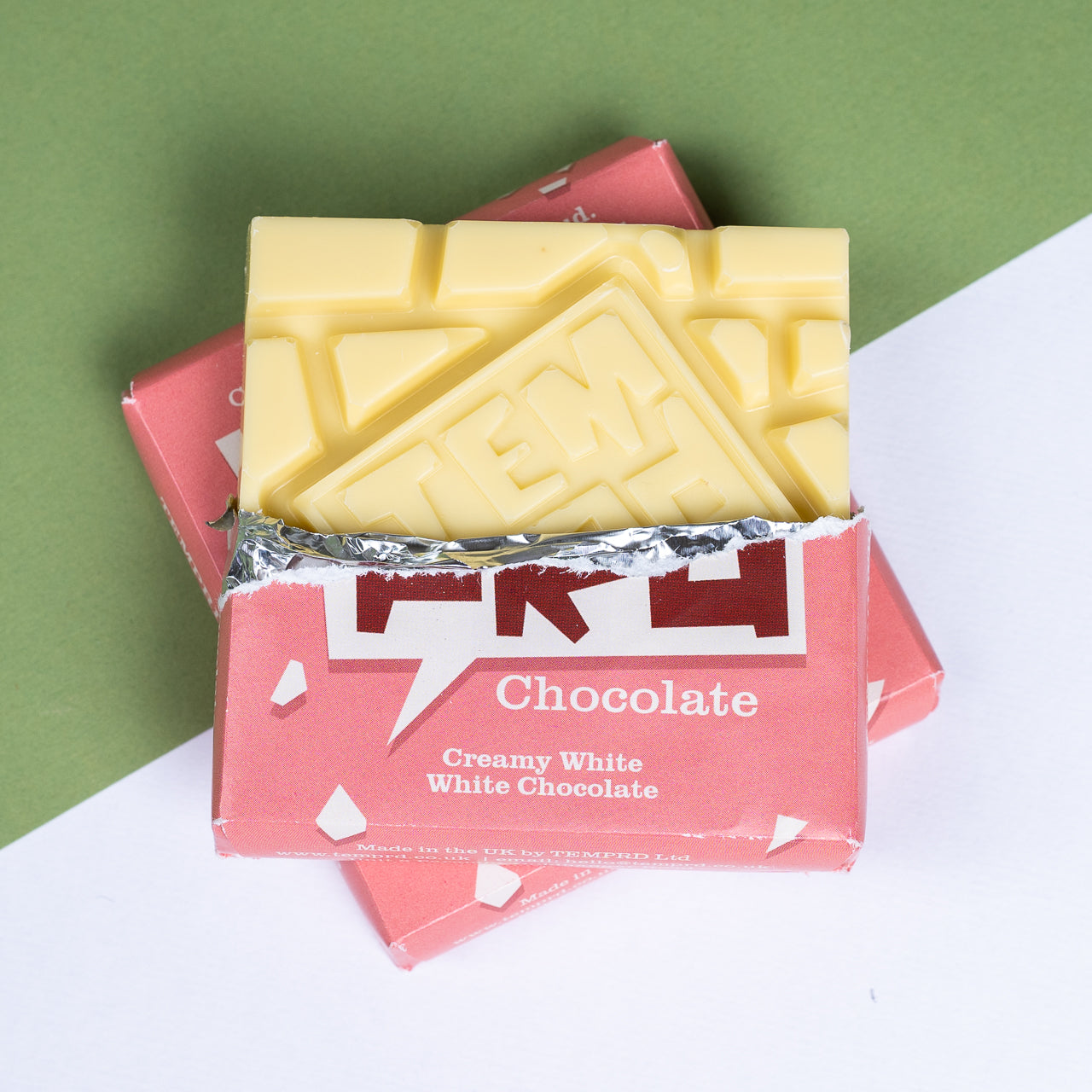 Bar of Temprd creamy white chocolate in a pink packaging on a green and white background available from Stort Valley Gifting