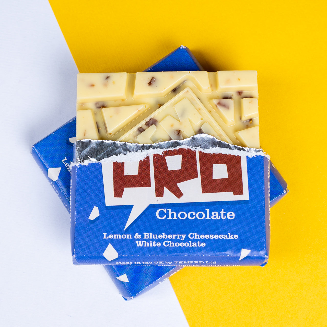 Temprd lemon & blueberry cheesecake flavoured white chocolate, on a yellow and white background available from Stort Valley Gifting