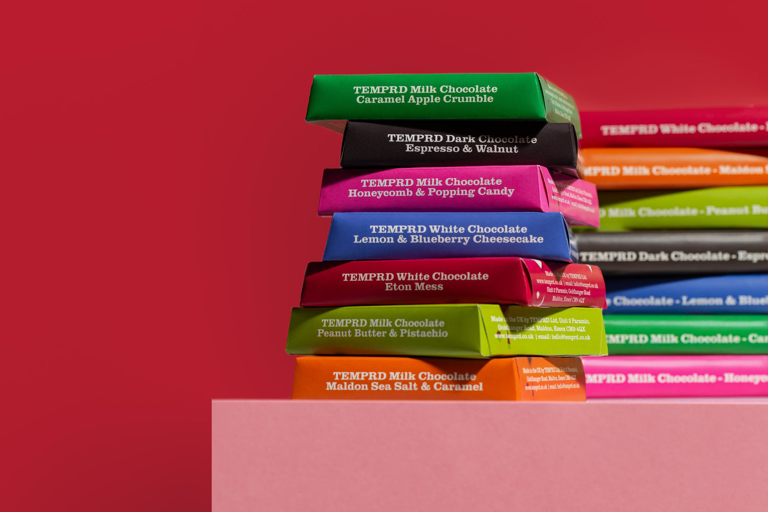 Stack of colorful chocolate bars with visible brand names on a red background
