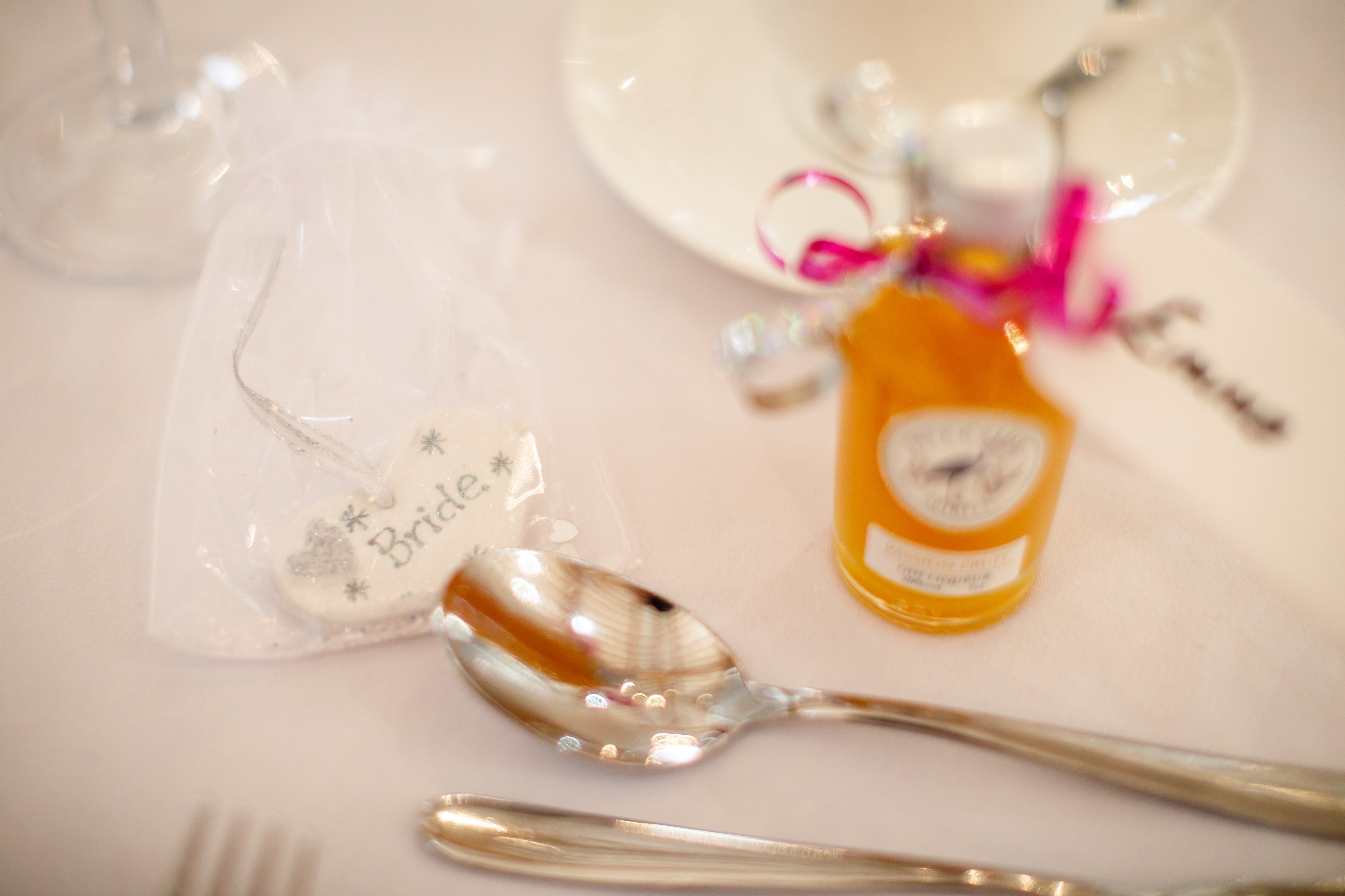 Silver spoon on a white surface with a small bottle and decorative item in the background.